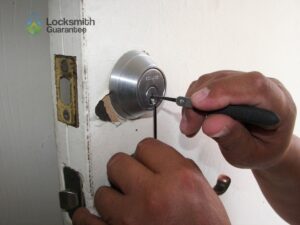 Hands picking a door lock with professional tools.