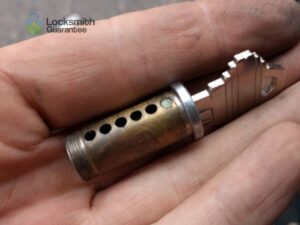 Hand holding a close-up view of a lock cylinder mechanism.