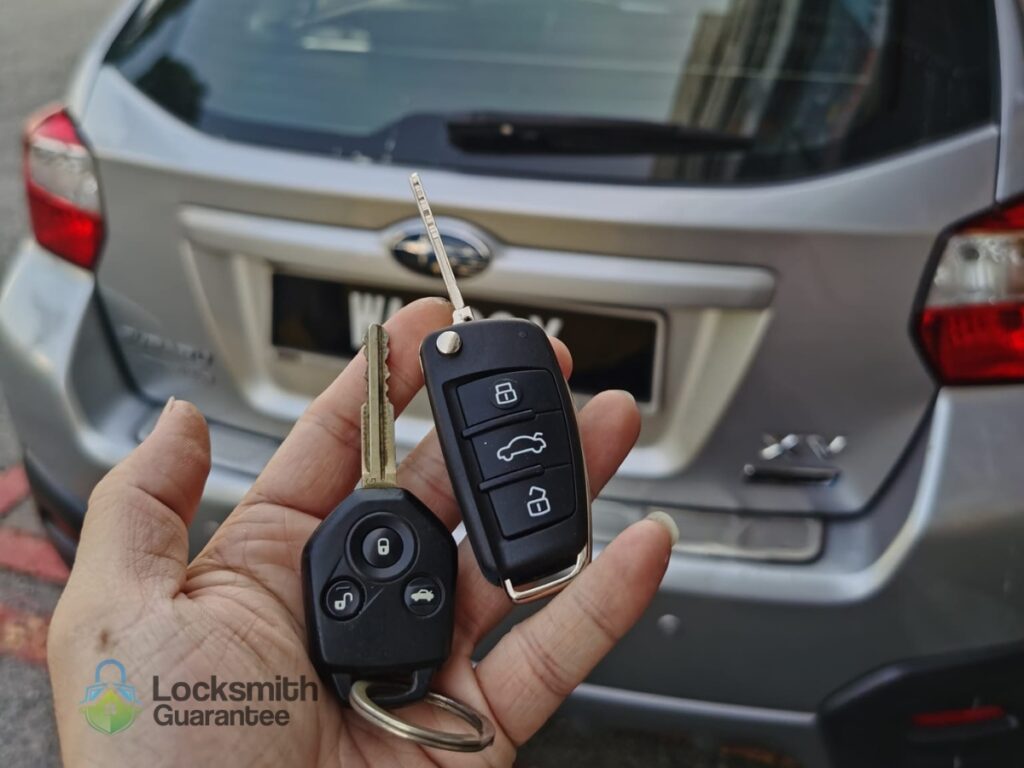 Hand holding car keys in front of a parked silver car.