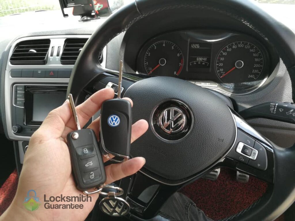 Hand holding two car keys inside a Volkswagen vehicle.